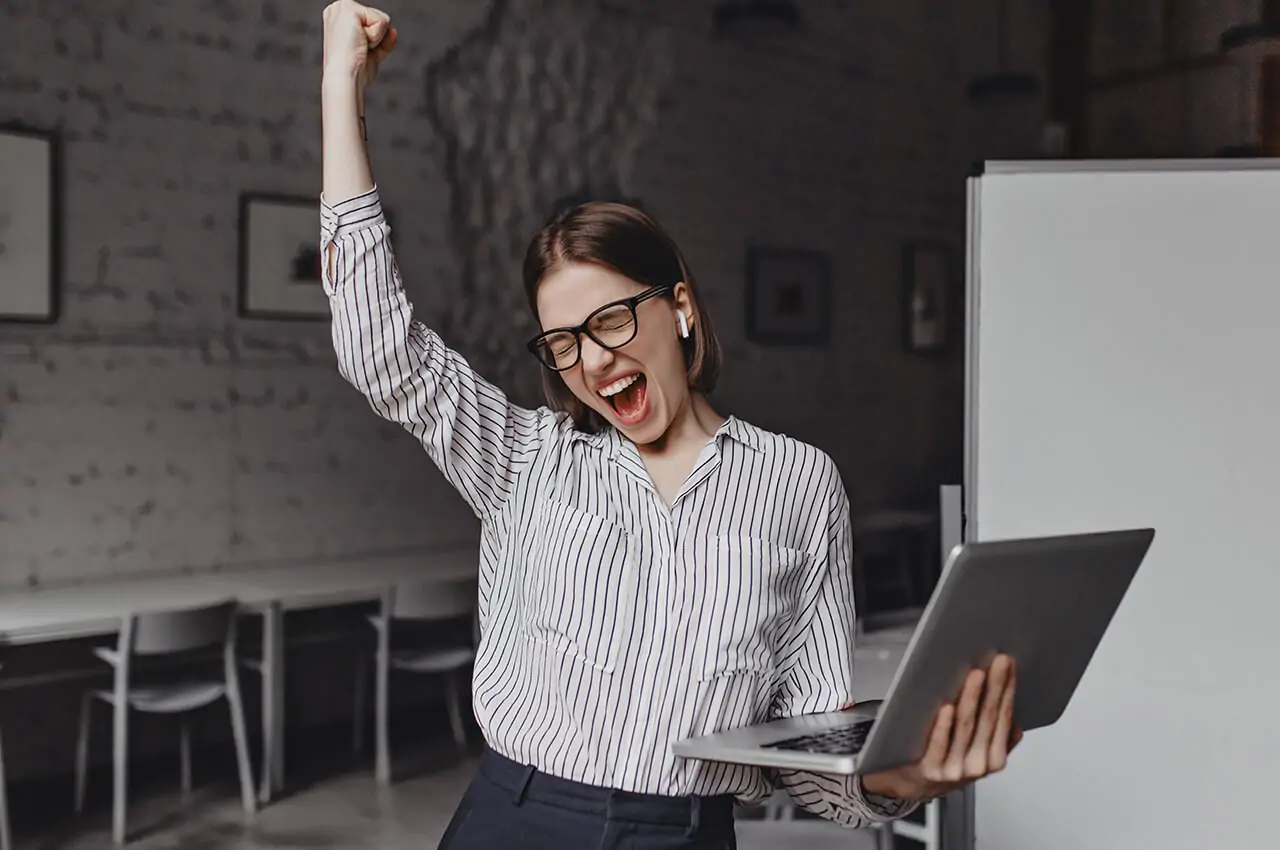 mulher com braço estendido feliz, com o notebook na mão após o evento corporativo