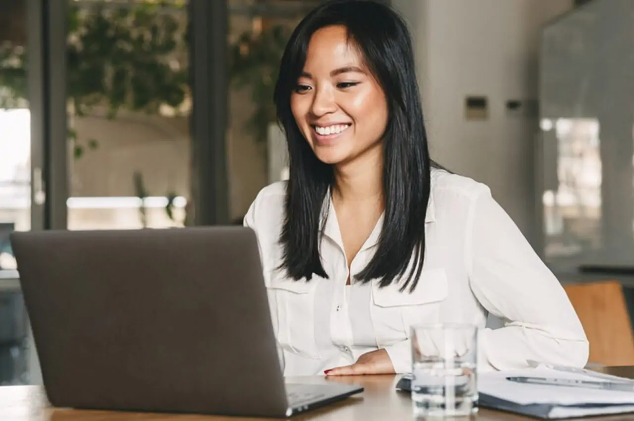 mulher sentada feliz olhando para o notebook na mesa após o evento corporativo