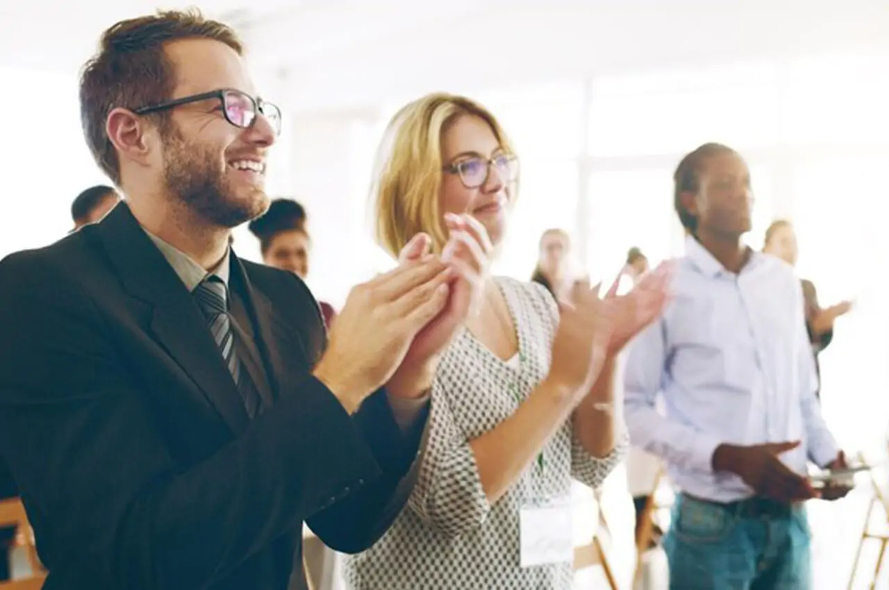 pessoas felizes de pé aplaudindo em um evento corporativo