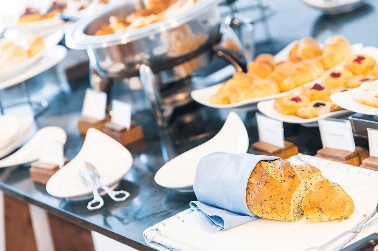 mesa com pães, doces e rechaud ao fundo