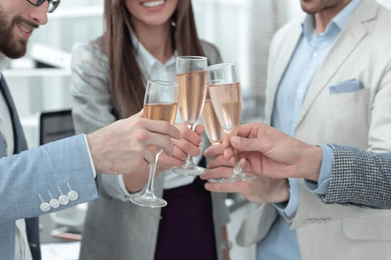 pessoas sorridentes brindando com taças de champanhe em festa de confraternização