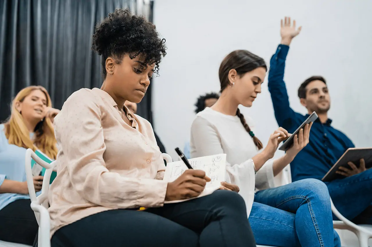pessoas em uma sala de evento sentados fazendo anotações
